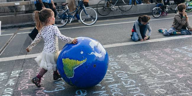 Child pushing globe at climate change protest