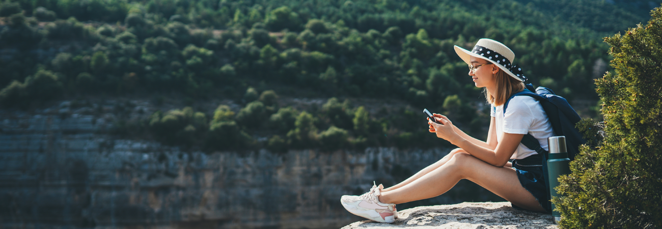 Woman on phone sitting on a cliff top